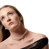 Woman wearing a pearl necklace against a plain background